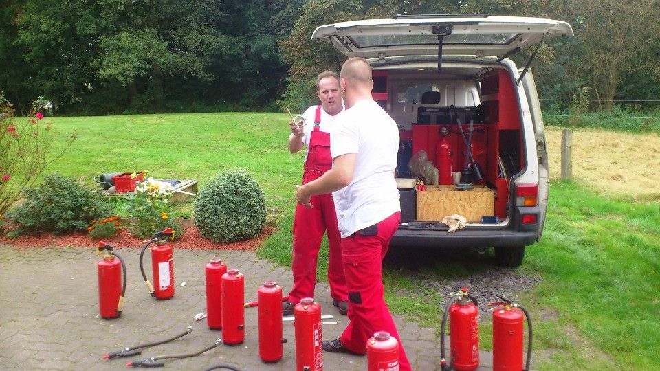 rote Feuermelder vor einem Auto mit offenem Gepäckraum