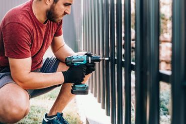 Person schraubt an einem Zaun