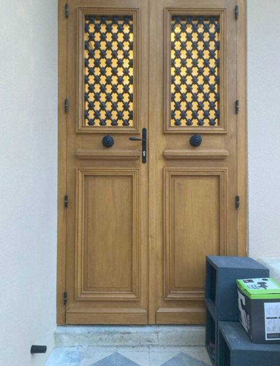 Porte double en bois avec panneaux de verre décoratifs et un petit paquet sur la droite