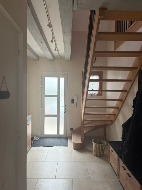 Couloir étroit avec porte d'entrée, escalier et banquette intégrée dans une maison moderne