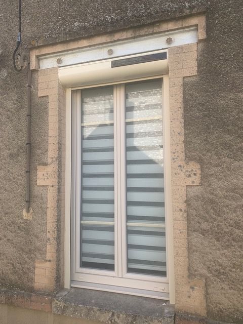 Fenêtre à double vitrage blanc à rayures dépolies encastrée dans un mur en pierre beige