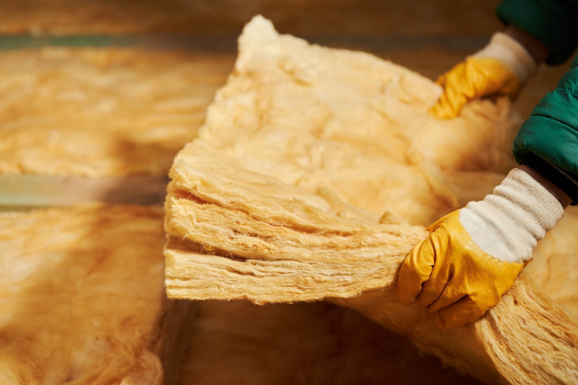 Personne portant des gants tenant une grande feuille d'isolant.