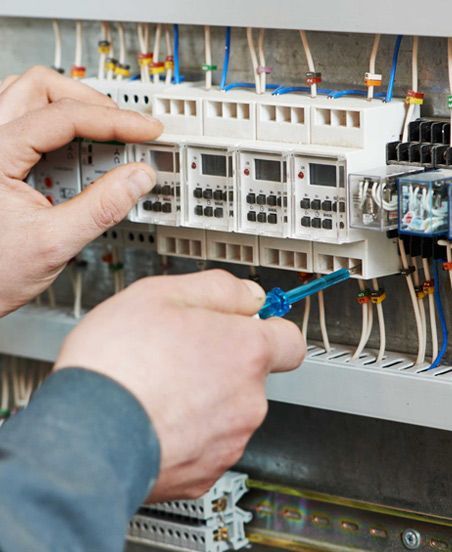 Una persona está trabajando en un panel eléctrico con un destornillador.