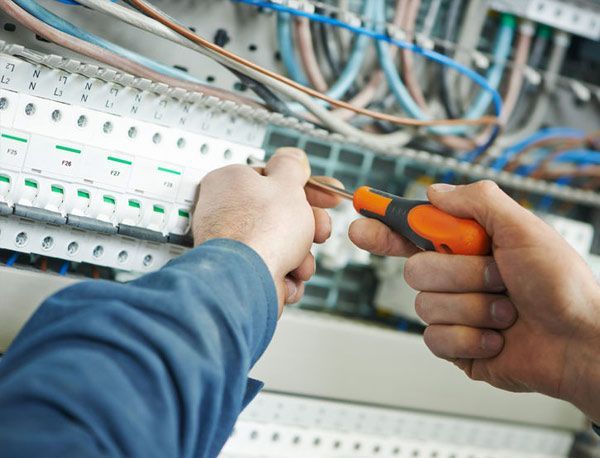 Un electricista está trabajando en una placa de circuito con un destornillador.