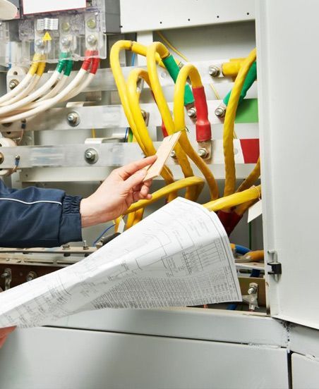 Una persona sostiene un trozo de papel delante de un montón de cables.