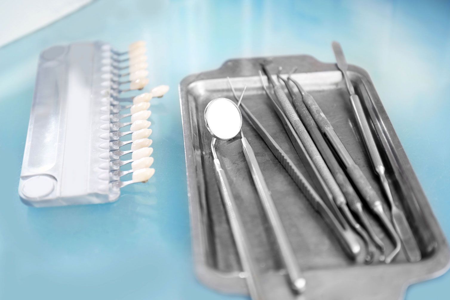 Una bandeja de instrumentos dentales y una bandeja de dientes sobre una mesa.