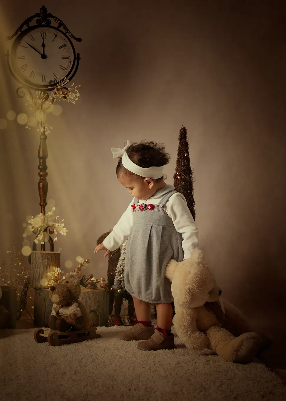 Un niño con overol mira un osito de peluche, junto a un reloj decorado y un árbol de Navidad, iluminado por un rayo de luz.