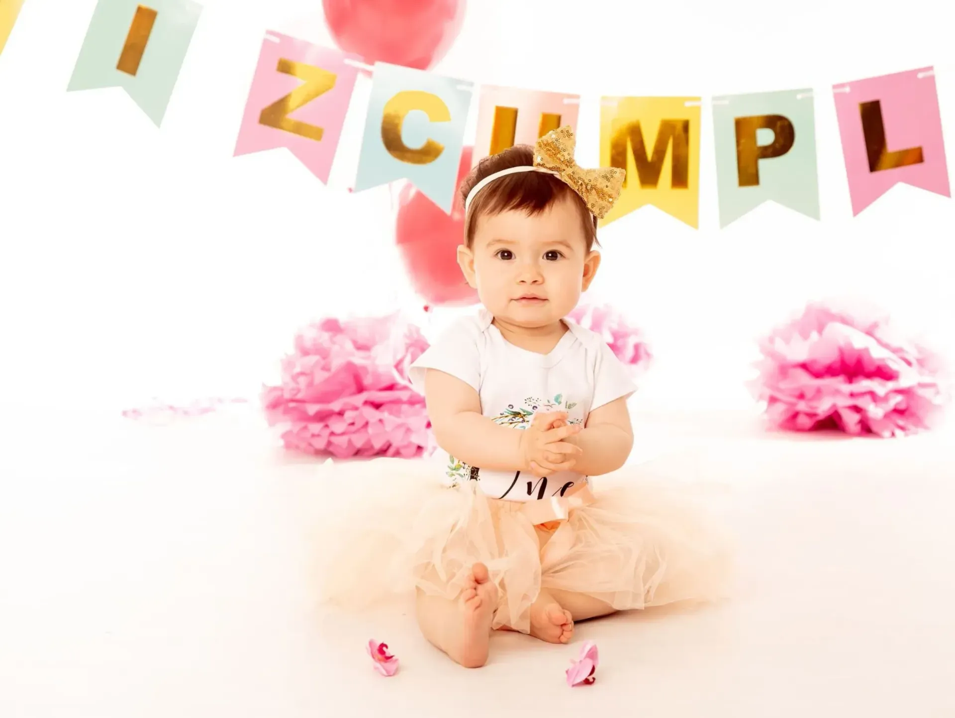 Bebé con corona, sentada frente a una pancarta que dice 
