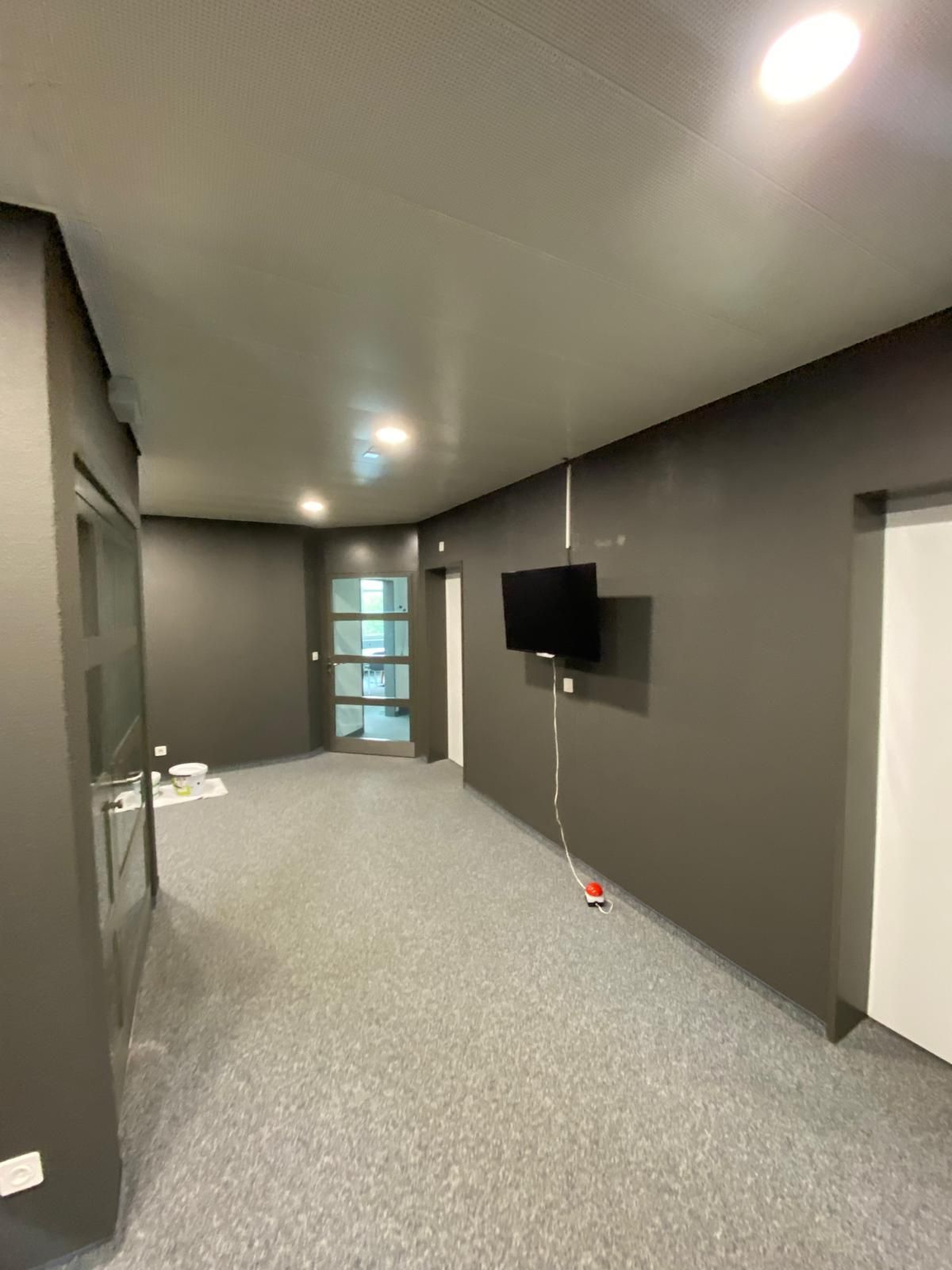 Weisser Schrank mit Dekoration und Kunstwerken an einer grau-weissen Wand, Tisch und Stühle rechts.