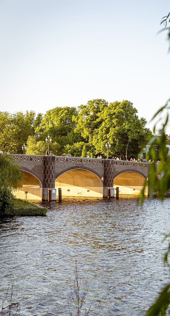 Eine Brücke über ein Gewässer mit Bäumen im Hintergrund.