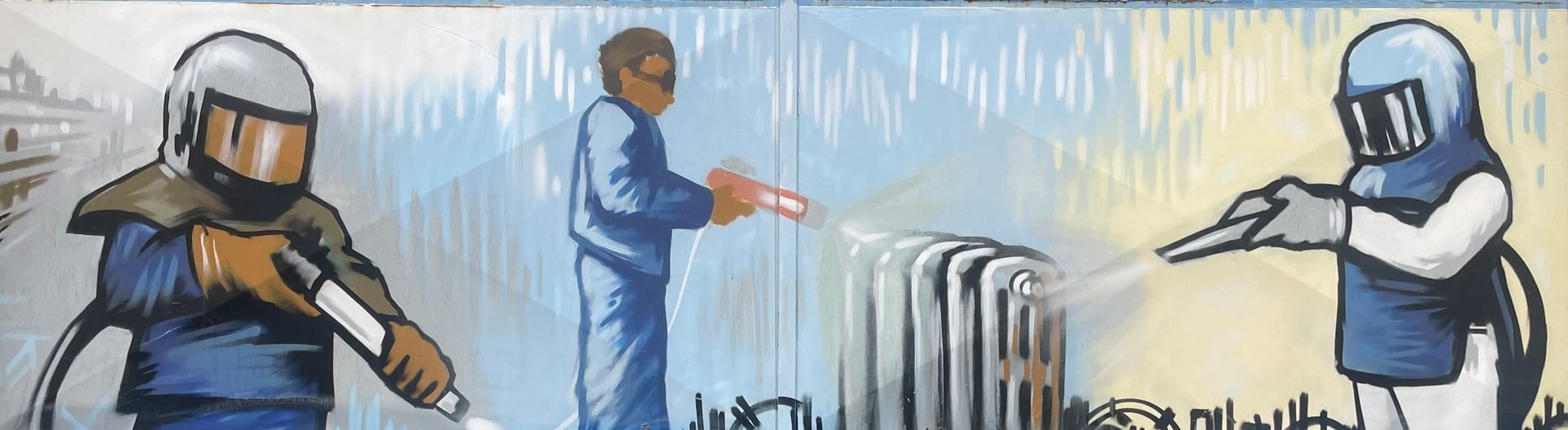 Trois ouvriers portant des équipements de protection pulvérisent une substance blanche.