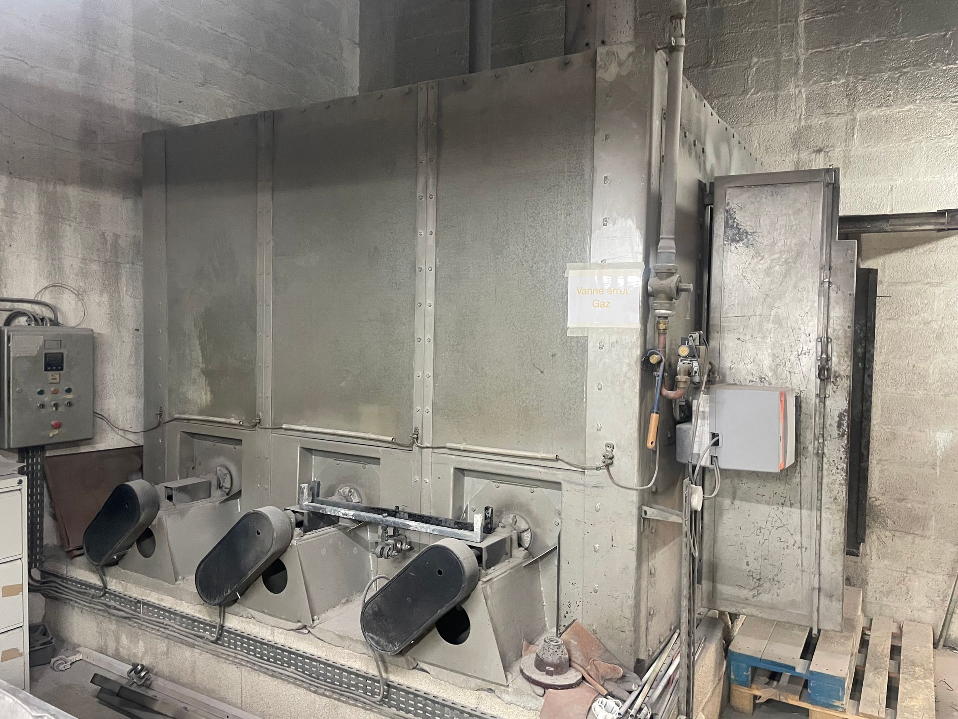 Grosse machine industrielle à plusieurs tambours rotatifs dans une salle en béton.