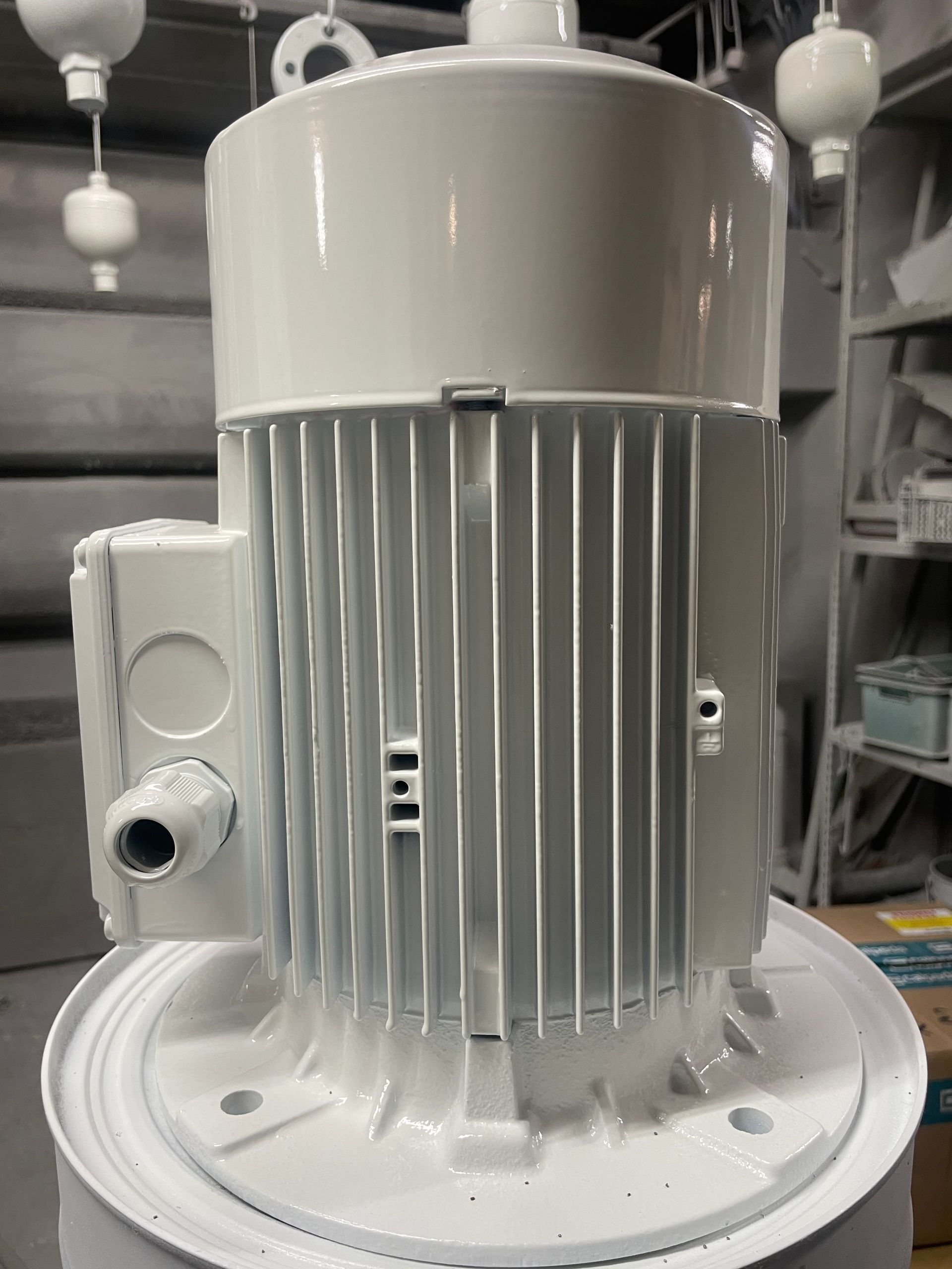 Moteur électrique industriel blanc avec ailettes de refroidissement, peint en atelier.