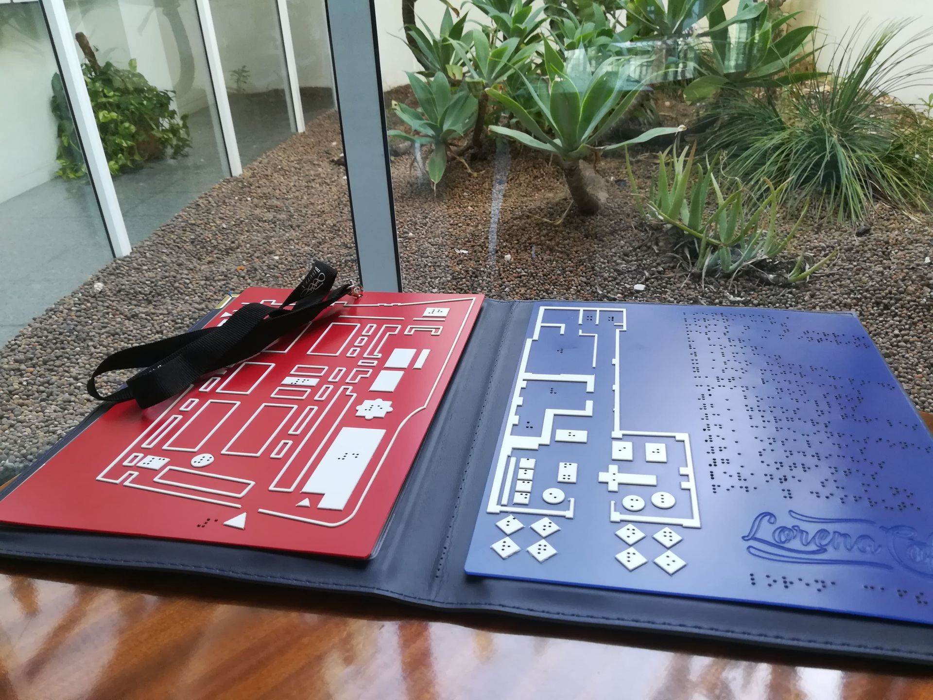 Un mapa braille rojo y uno azul están sobre una mesa