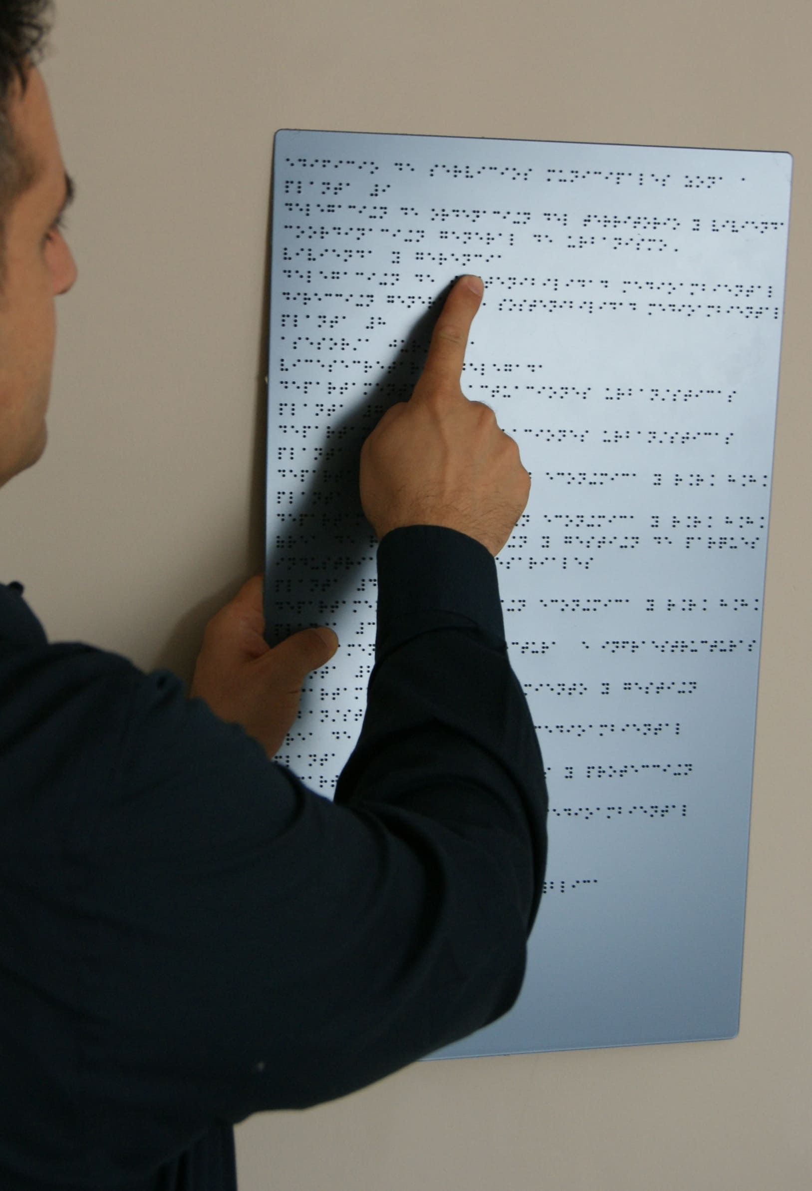 Un hombre señala un trozo de papel en una pared.