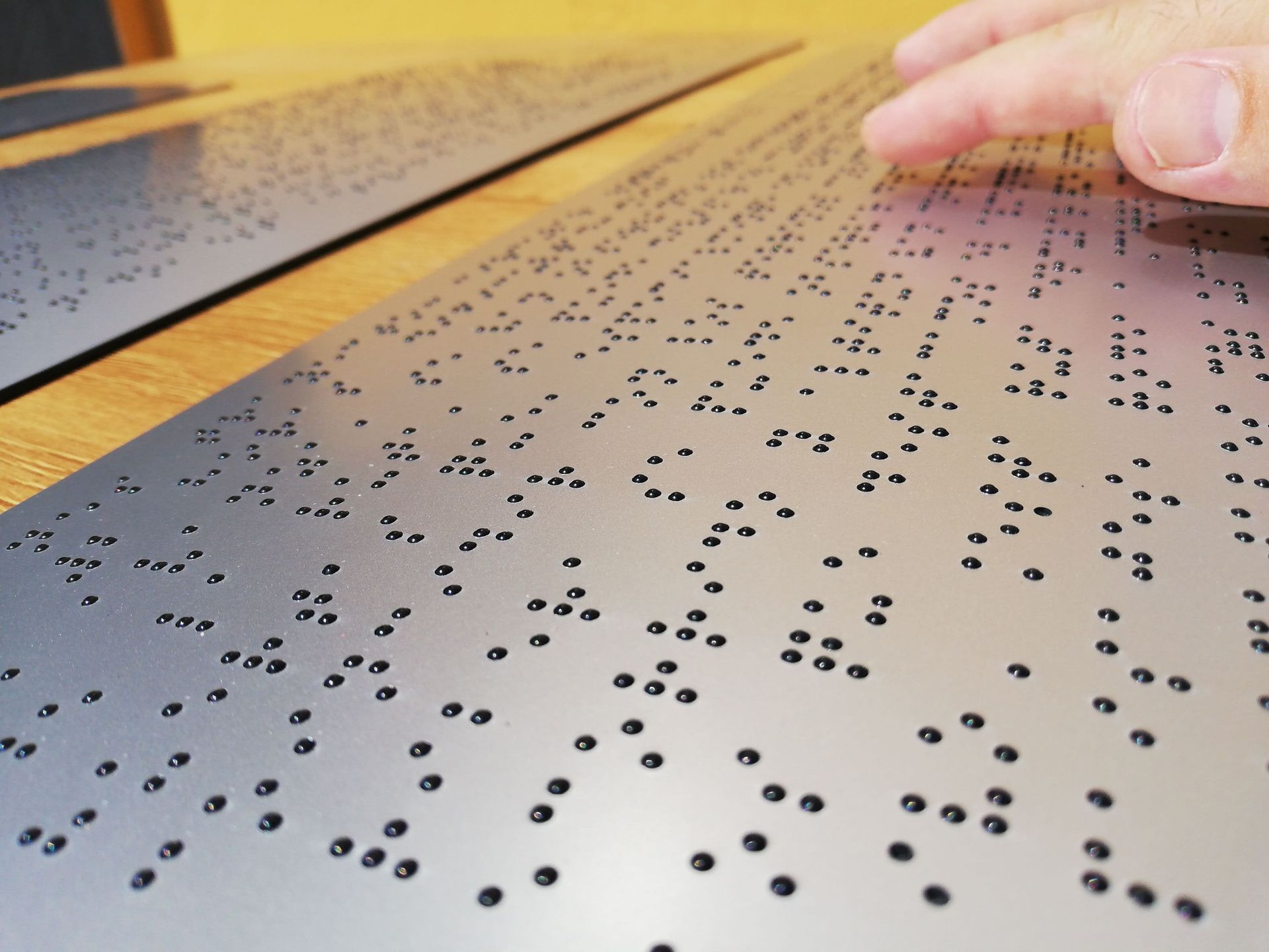 Una persona está leyendo braille en un trozo de metal.