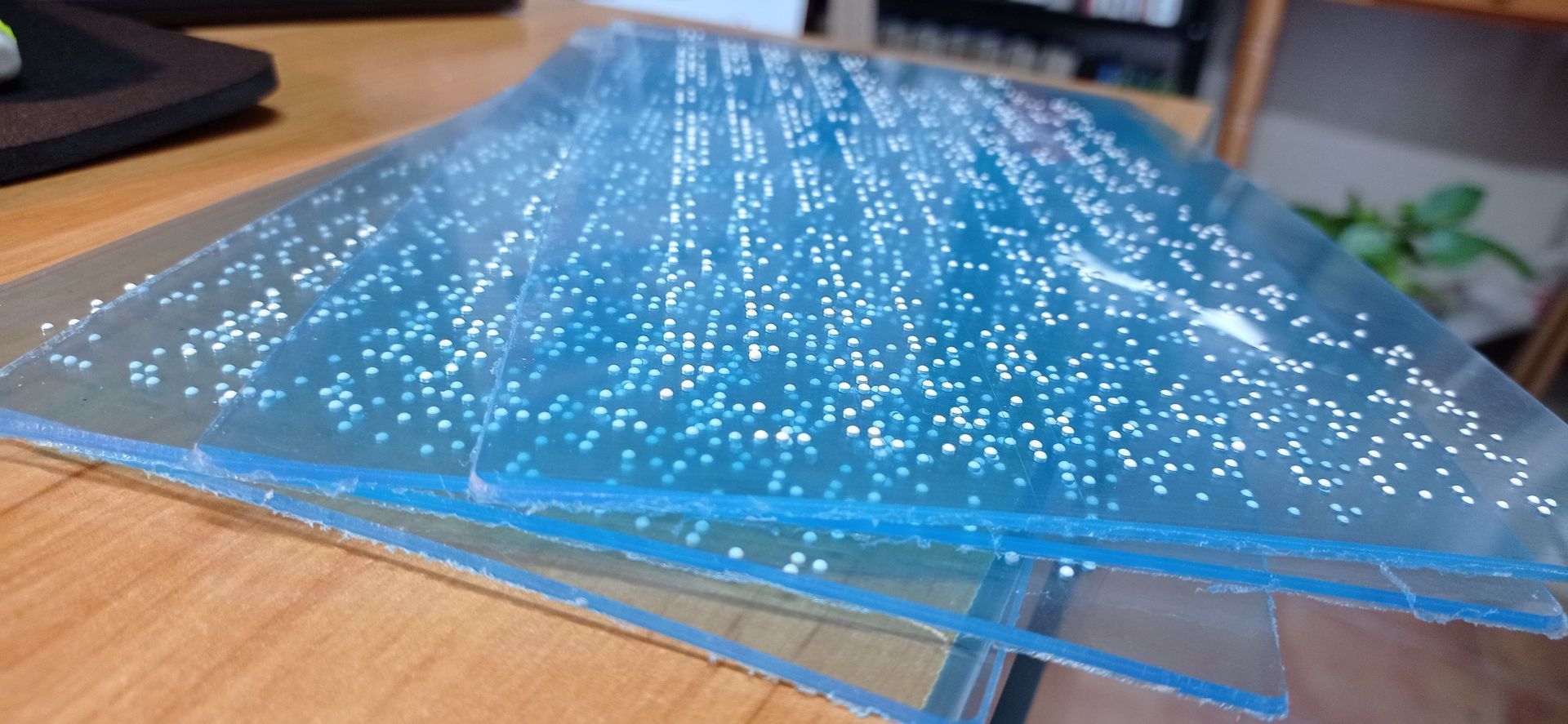 Tres piezas de plástico transparente están apiladas una encima de otra sobre una mesa de madera.