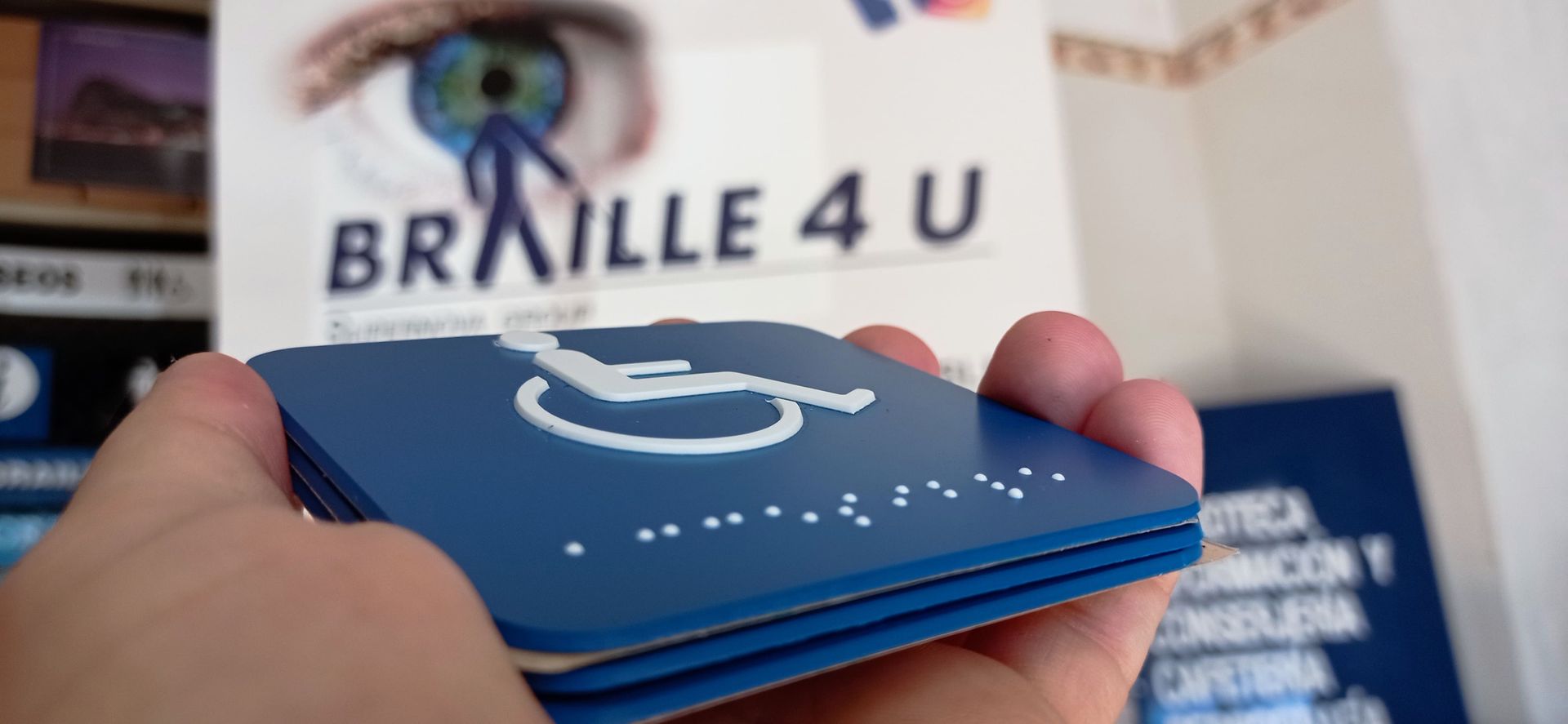 Una persona sostiene un cartel braille 4 u en su mano.