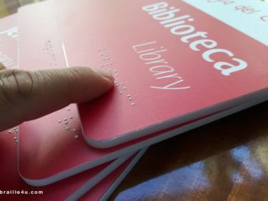 Una persona está señalando un cartel rojo que dice biblioteca