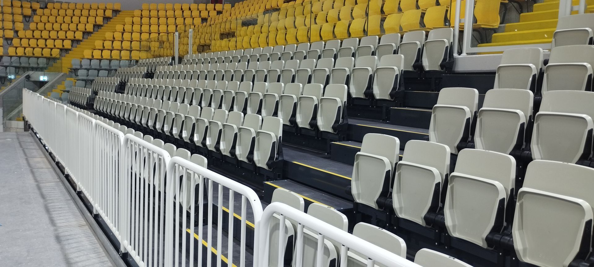 A row of empty seats in a stadium with a white fence.