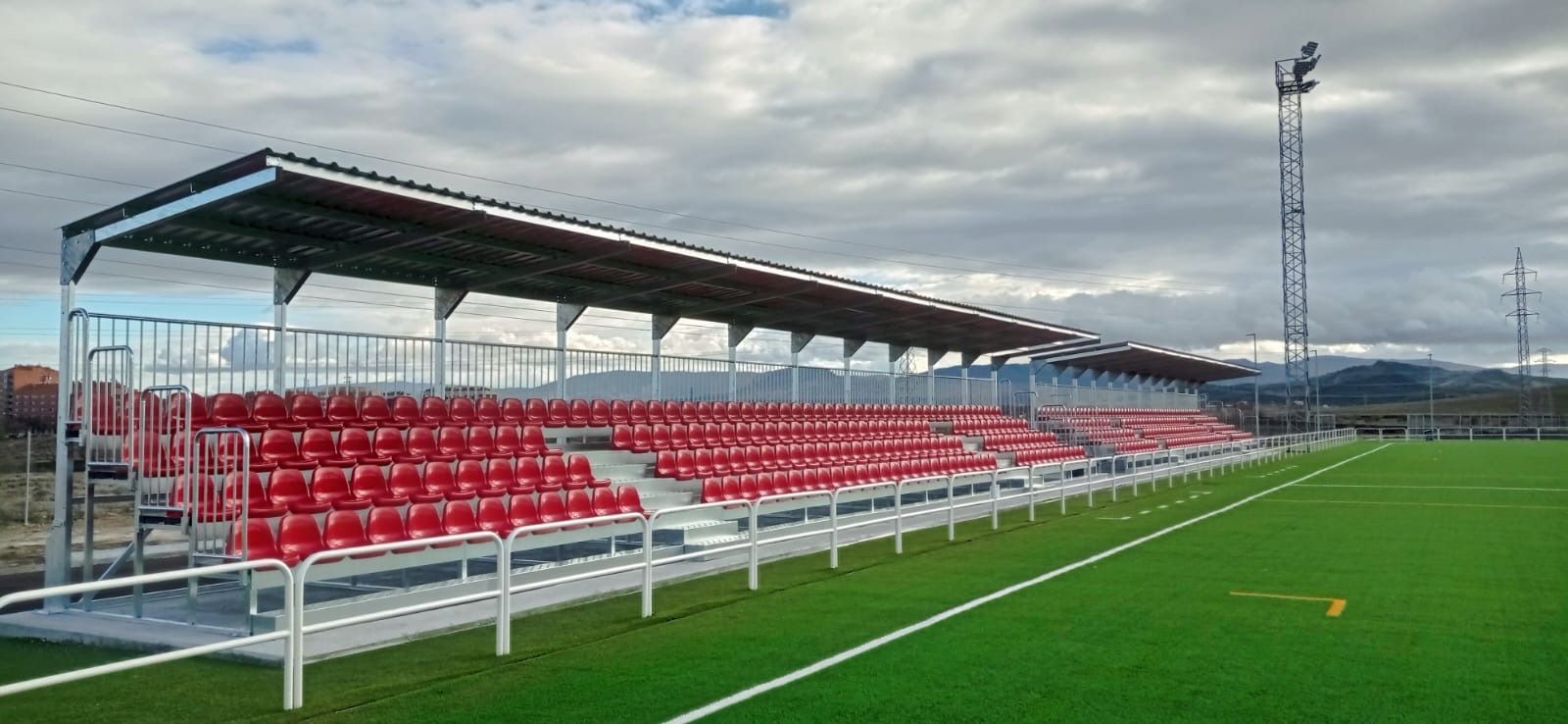 Un campo de fútbol con asientos rojos y techo.