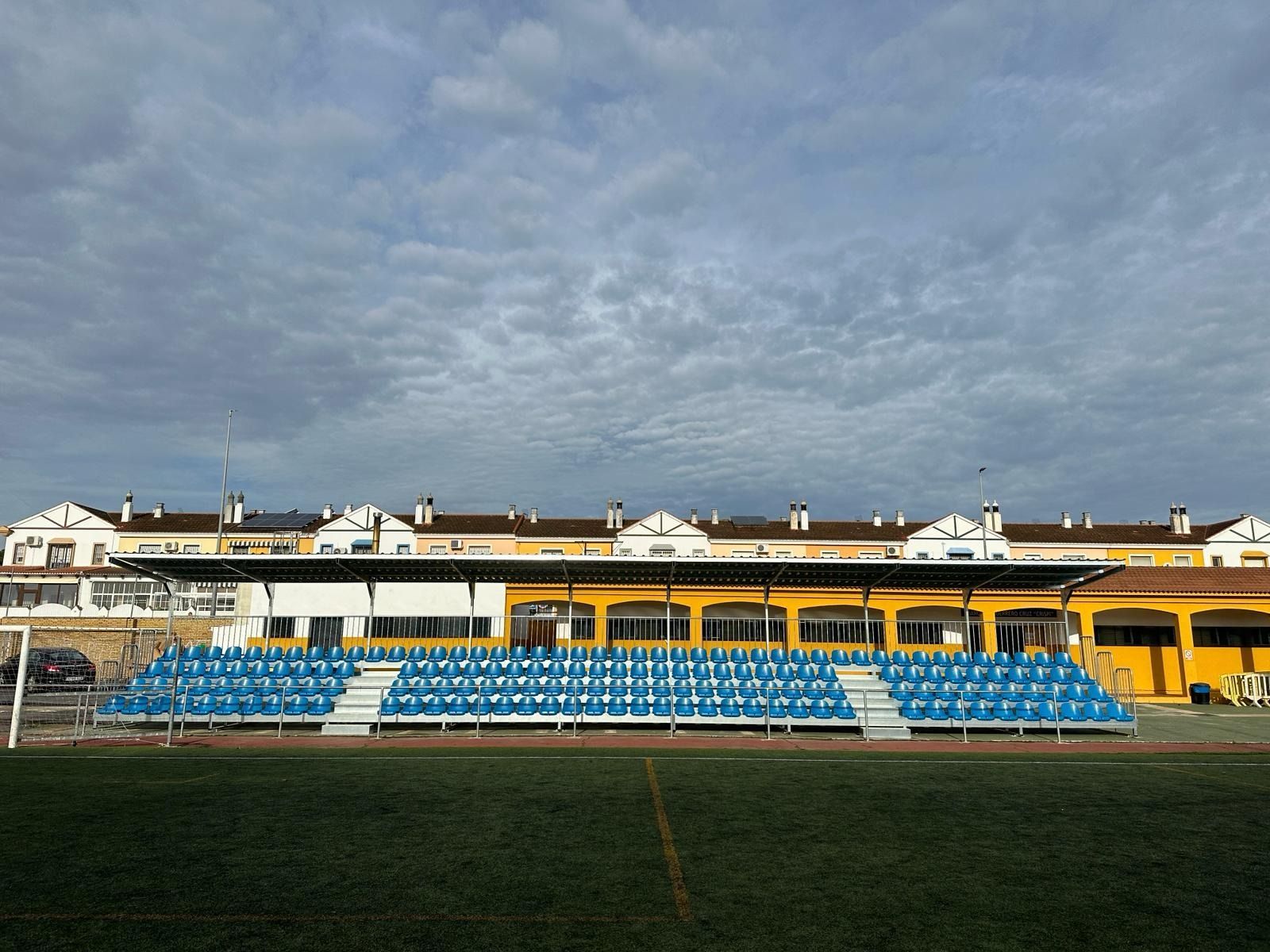 Un estadio con asientos azules y un edificio amarillo al fondo.