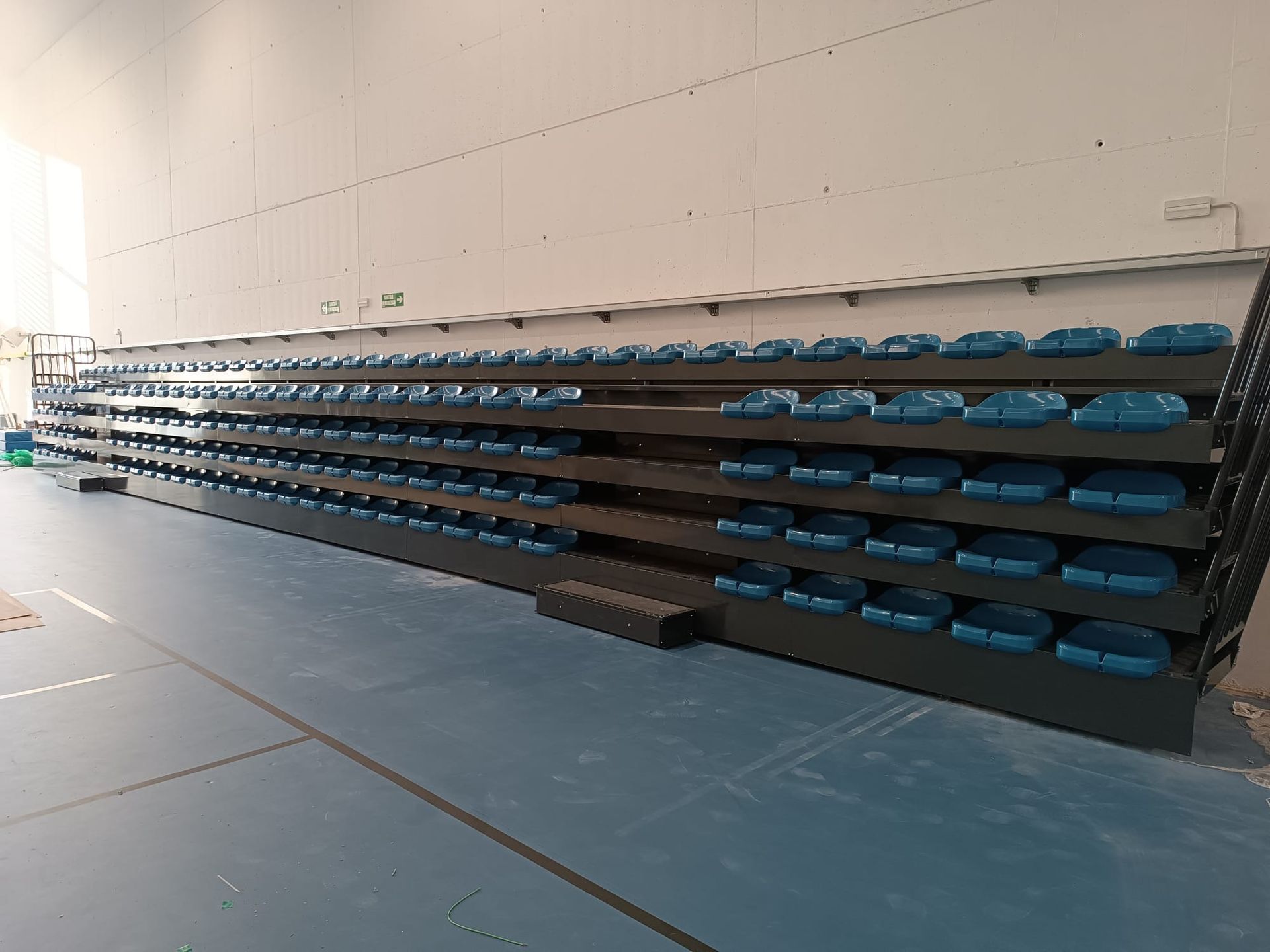 Una fila de gradas en un gimnasio con asientos azules.