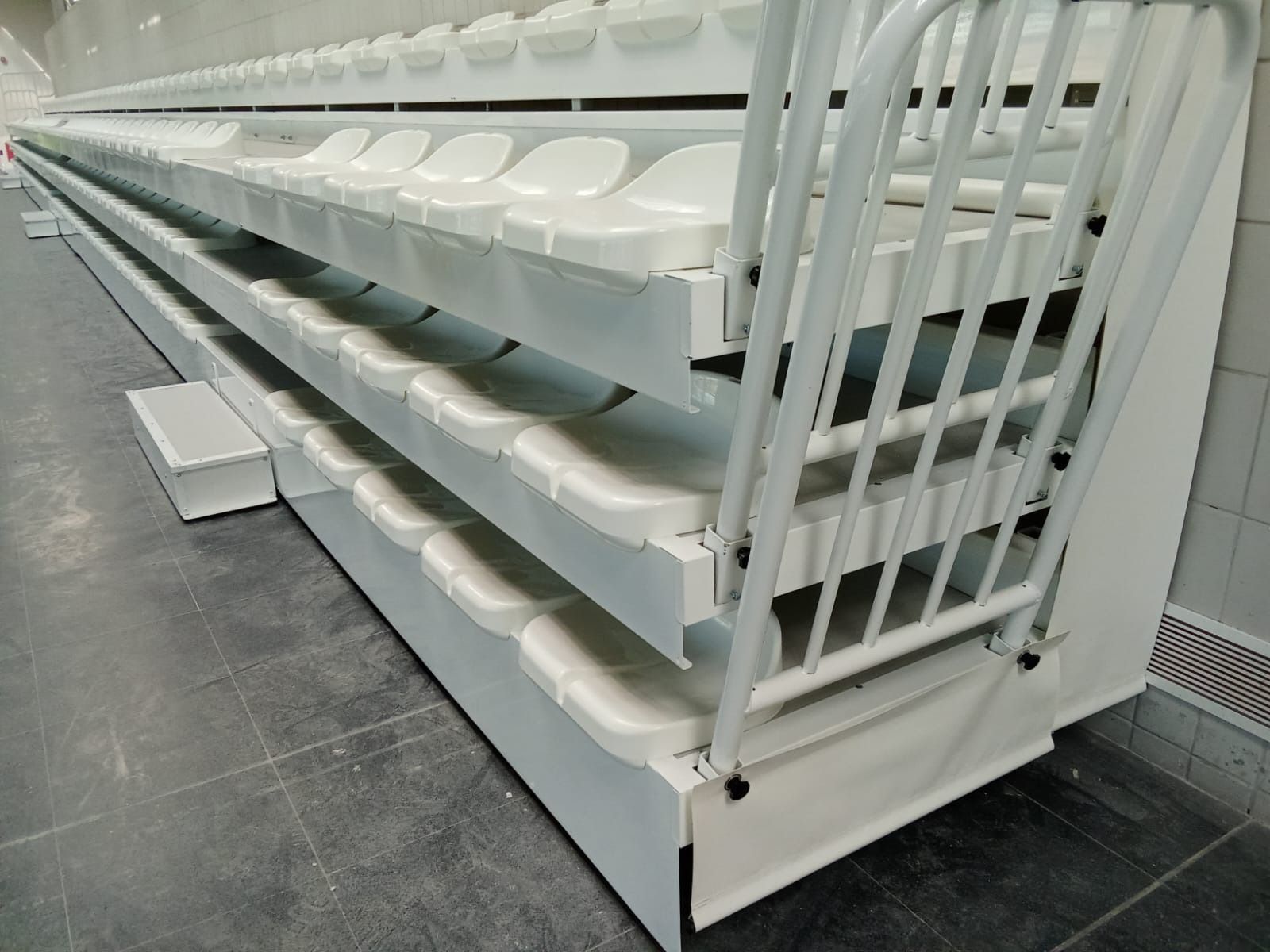 Una fila de asientos de plástico blanco están apilados uno encima del otro en un estadio.