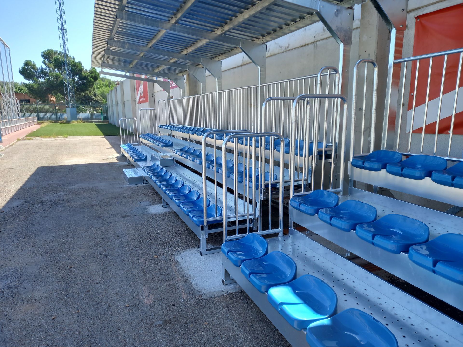 Una fila de gradas con asientos azules y una barandilla de metal.