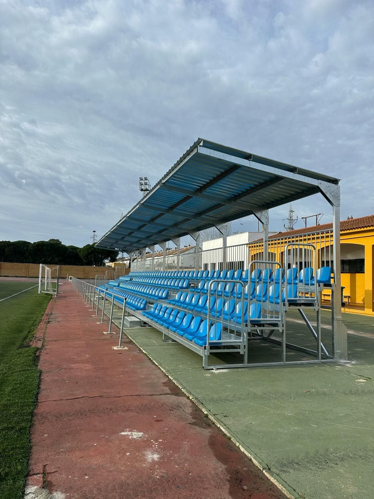 Una fila de asientos azules en un estadio con un dosel sobre ellos.