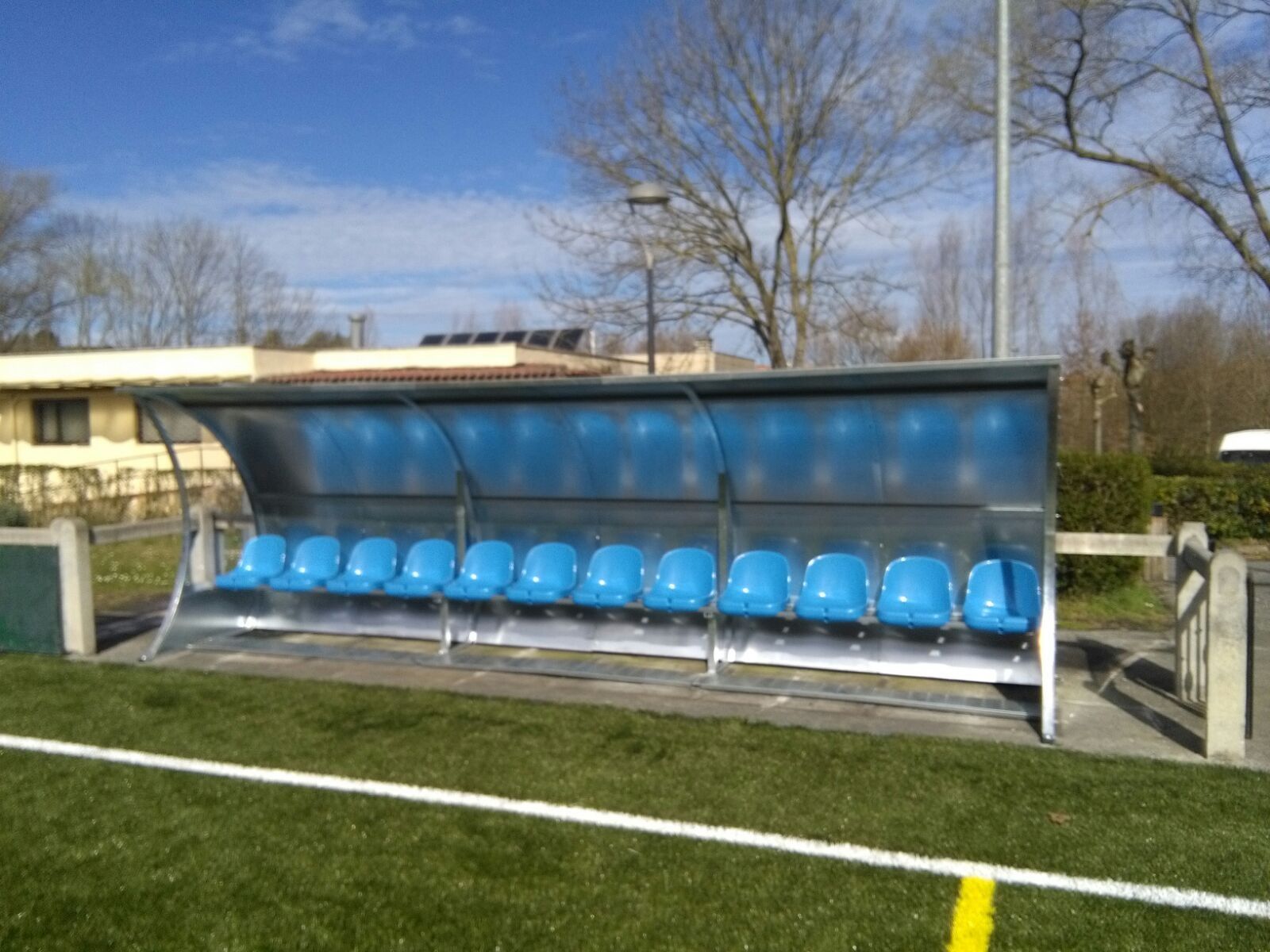 Un campo de fútbol con un refugio con asientos azules.