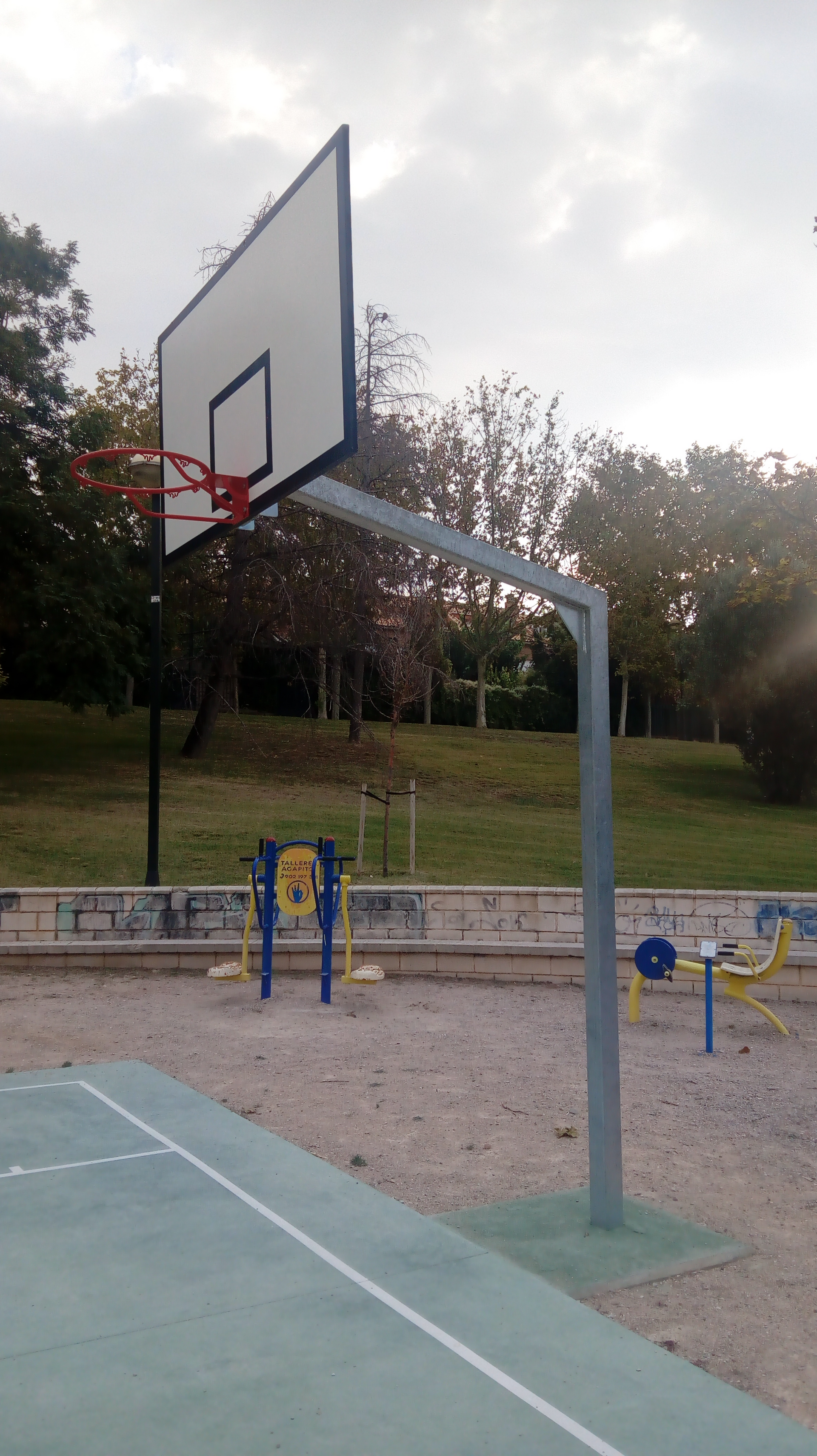 Un aro de baloncesto está encima de una cancha de baloncesto en un parque.