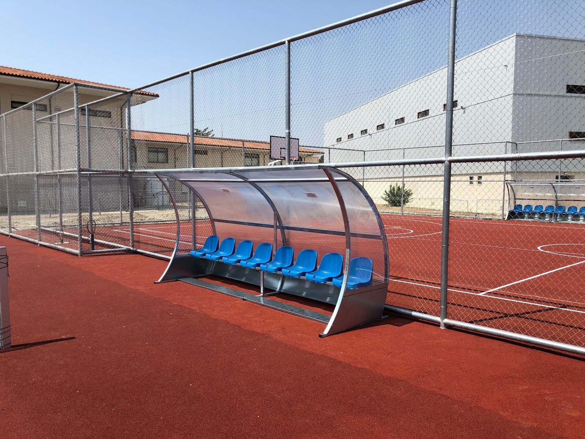 Un campo de fútbol con un refugio y asientos azules.
