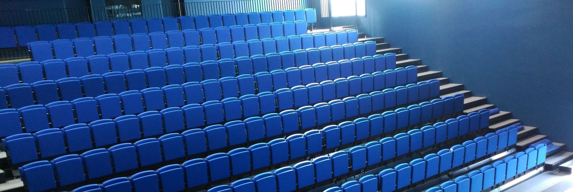 Una fila de sillas azules están alineadas en un auditorio.