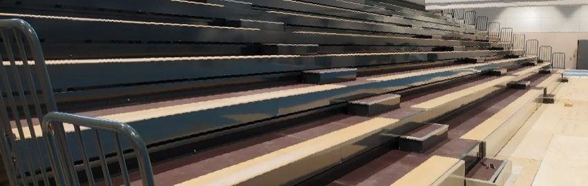 Una fila de gradas en un estadio con suelo de madera.