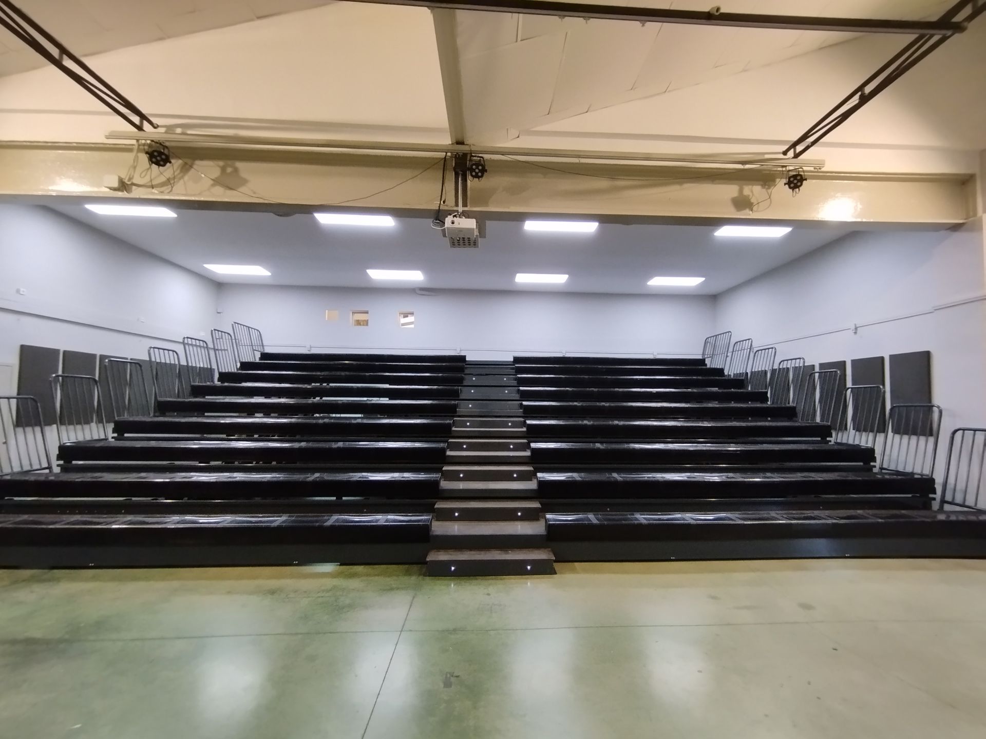 Un auditorio vacío con asientos negros y escaleras.