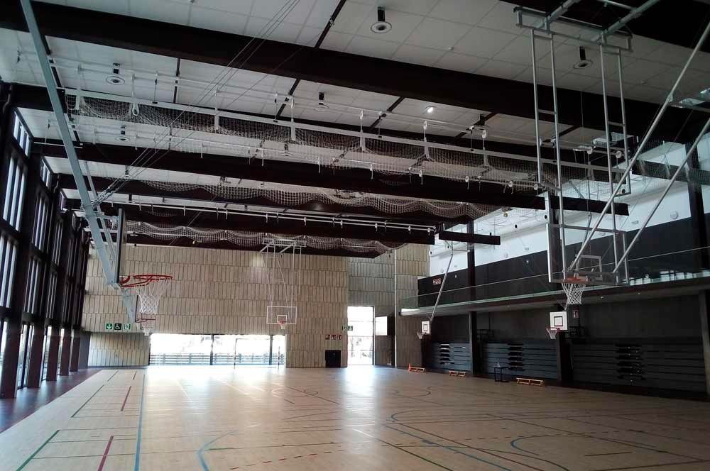 Un gimnasio vacío con un aro de baloncesto y una escalera.