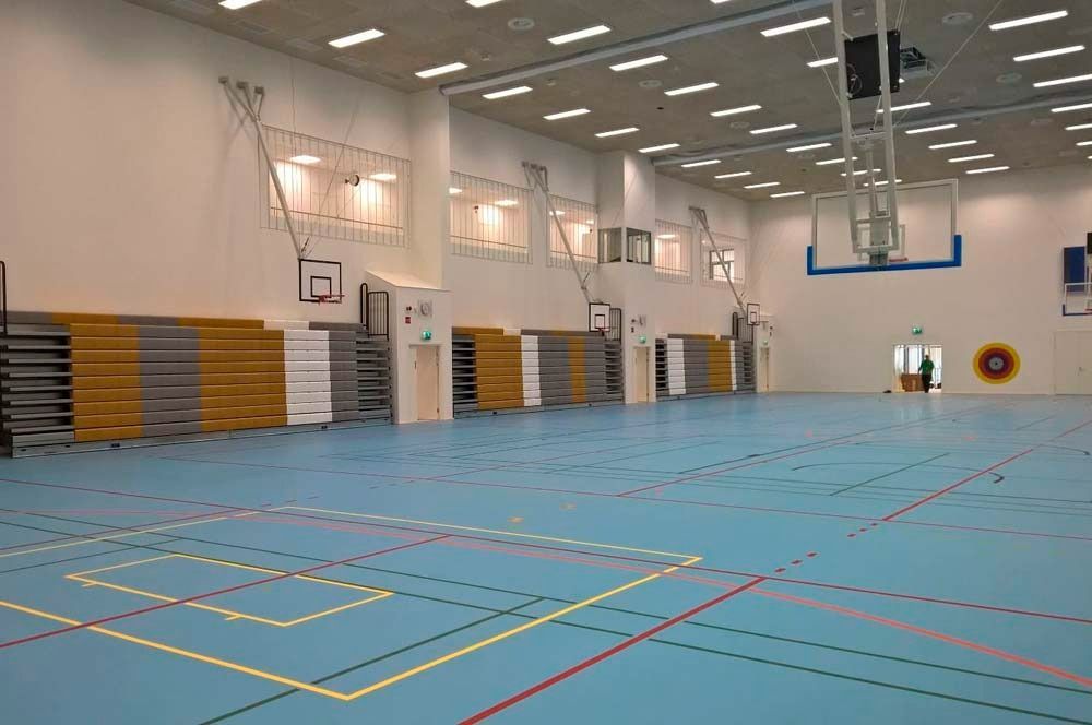 Un gimnasio vacío con un aro de baloncesto en la pared.