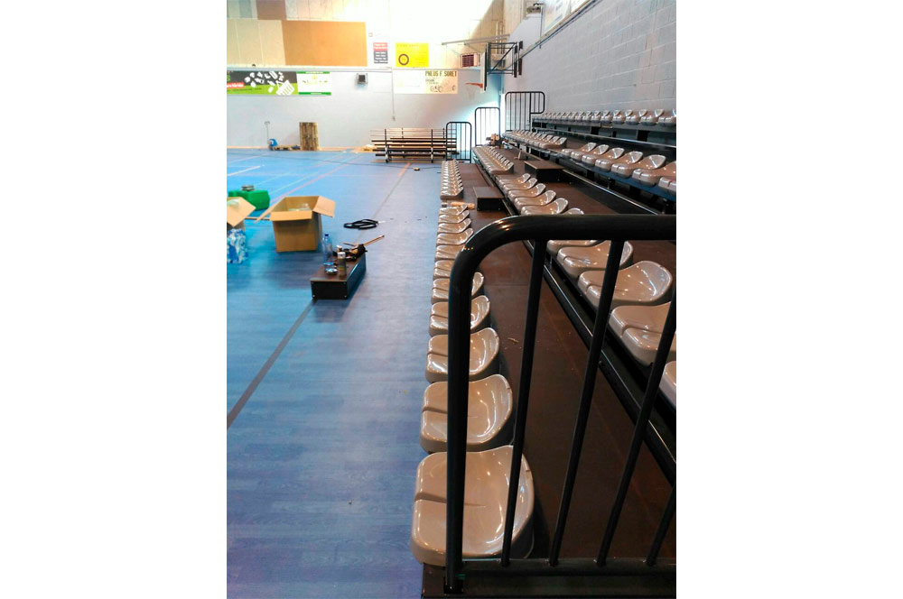 Una fila de gradas en un gimnasio con suelo azul.