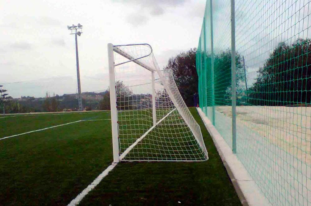 Una portería de fútbol en un campo con una valla alrededor.
