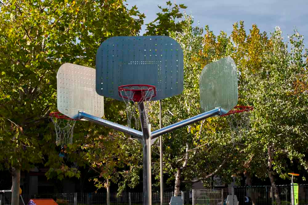 Un aro de baloncesto en un parque con árboles al fondo.