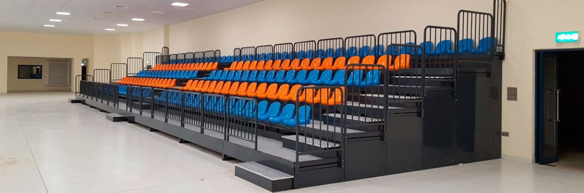 Una fila de asientos azules y naranjas en un estadio.