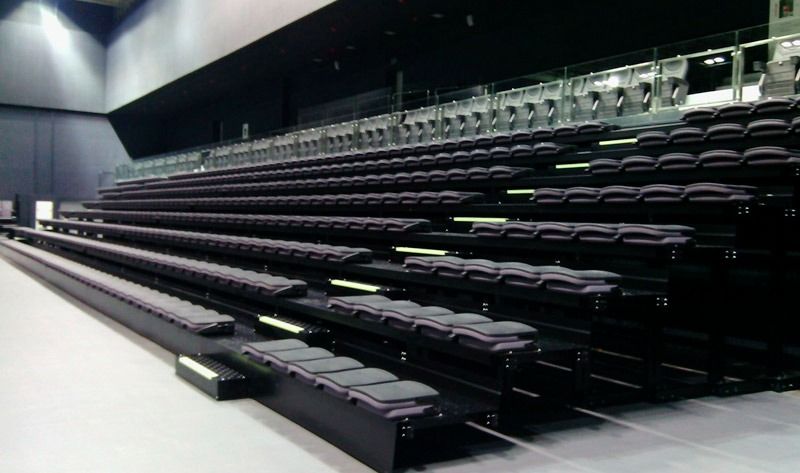 Una fila de asientos de estadio vacíos en una habitación oscura