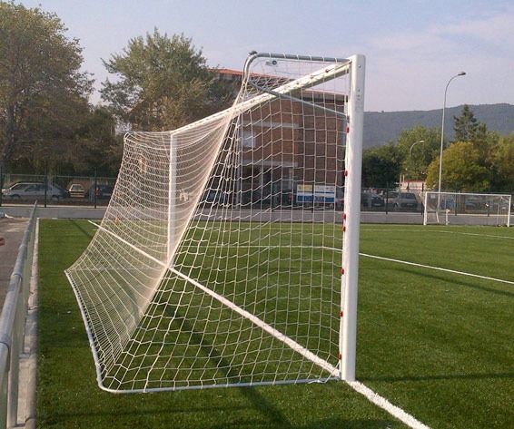 Una portería de fútbol en un campo con un edificio al fondo