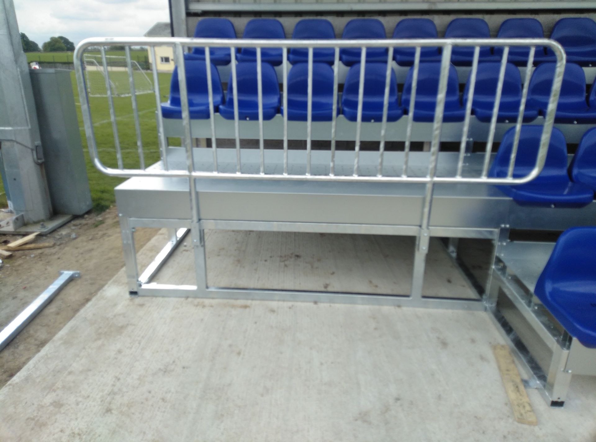 Un estadio con asientos azules y una barandilla de metal.