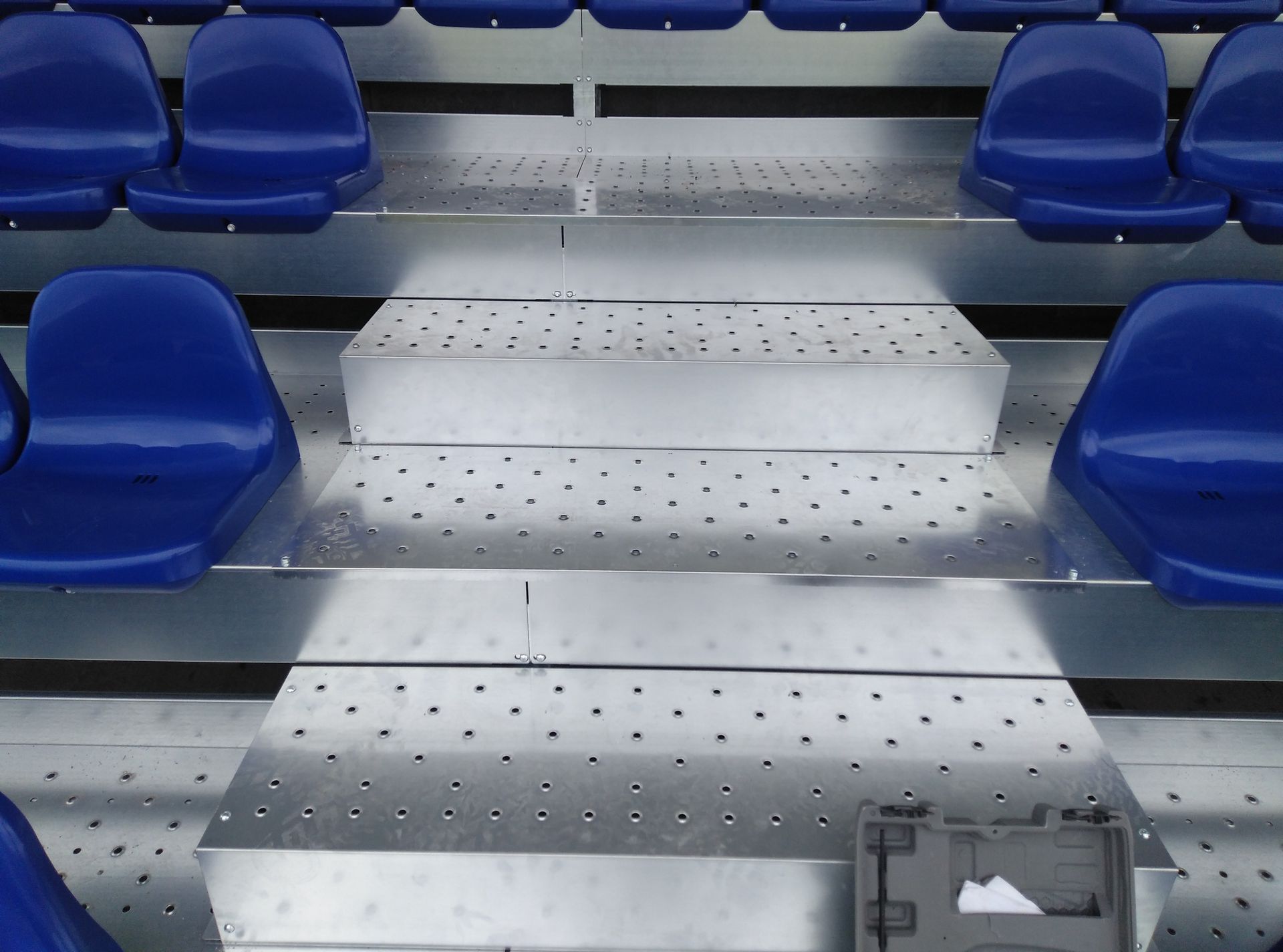 Una fila de asientos azules en una grada de metal