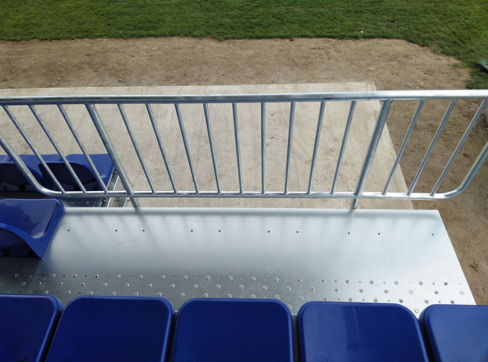 Un estadio con asientos azules y una barandilla de metal.