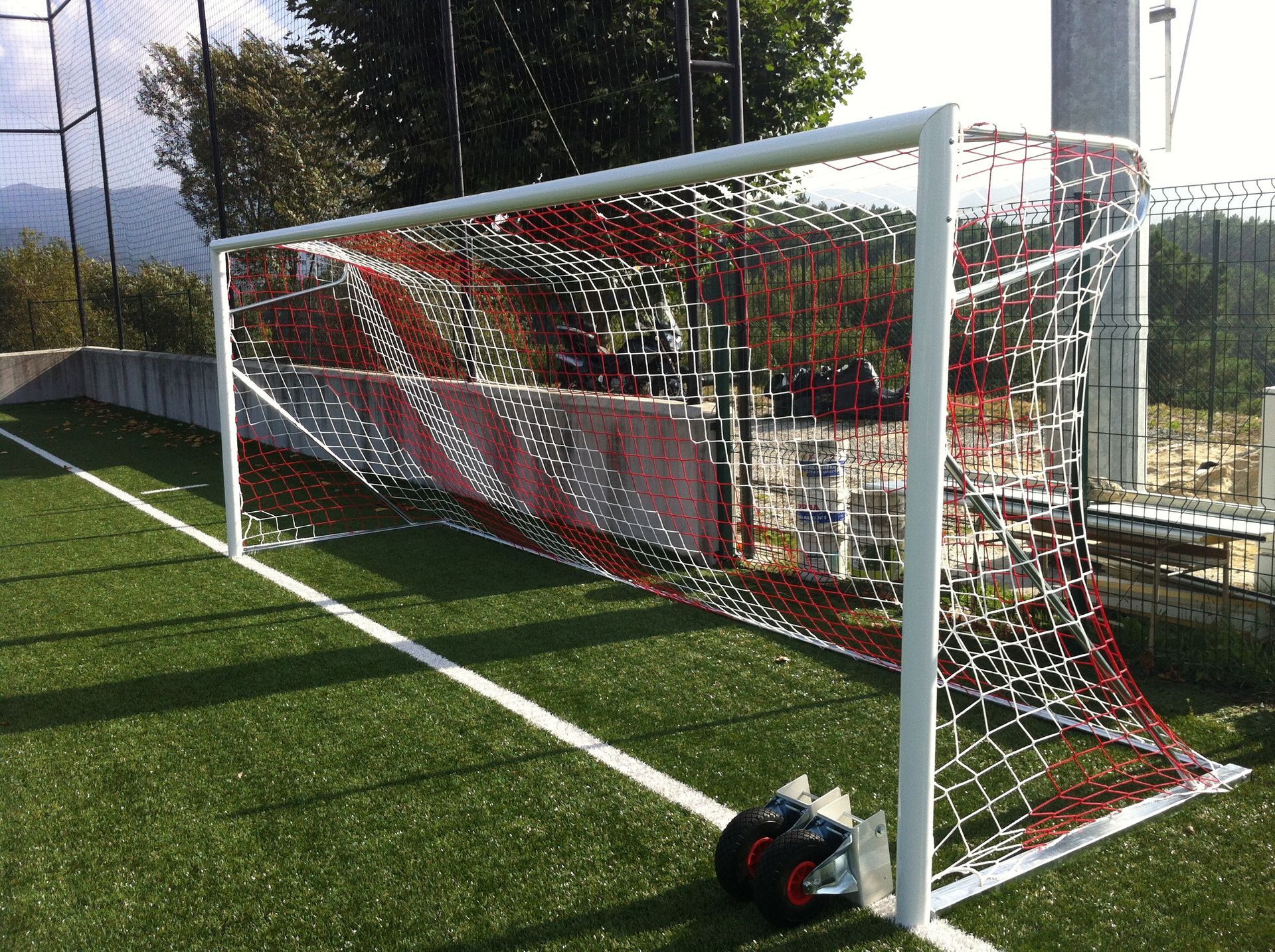 Un par de botines de fútbol están colocados al costado de una portería de fútbol.