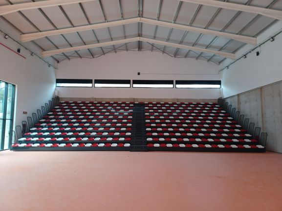 Un auditorio vacío con filas de asientos rojos y blancos