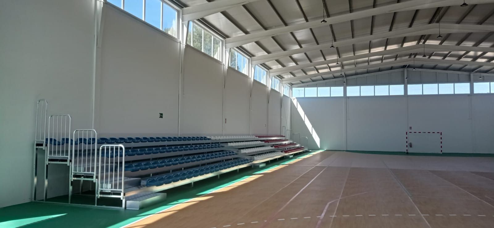 Un gimnasio vacío con gradas y una cancha de baloncesto.